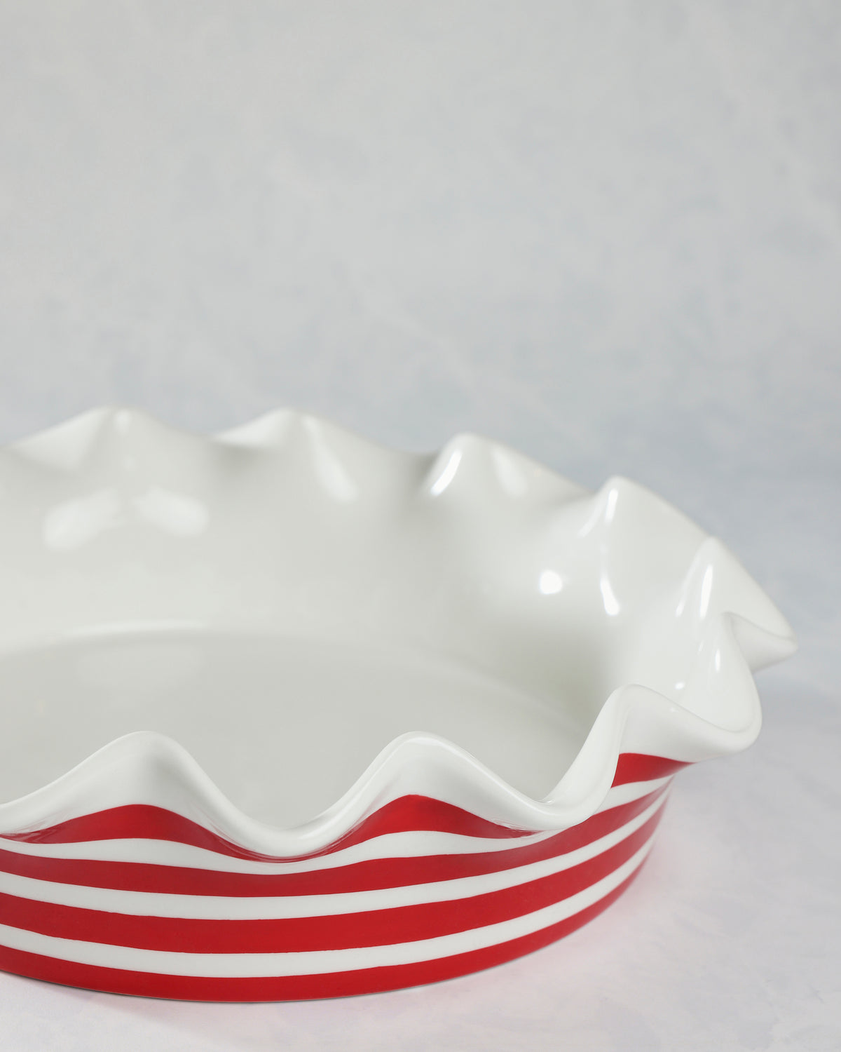 Red-and-white striped pie dish with a wavy ruffled rim, shown from the side.