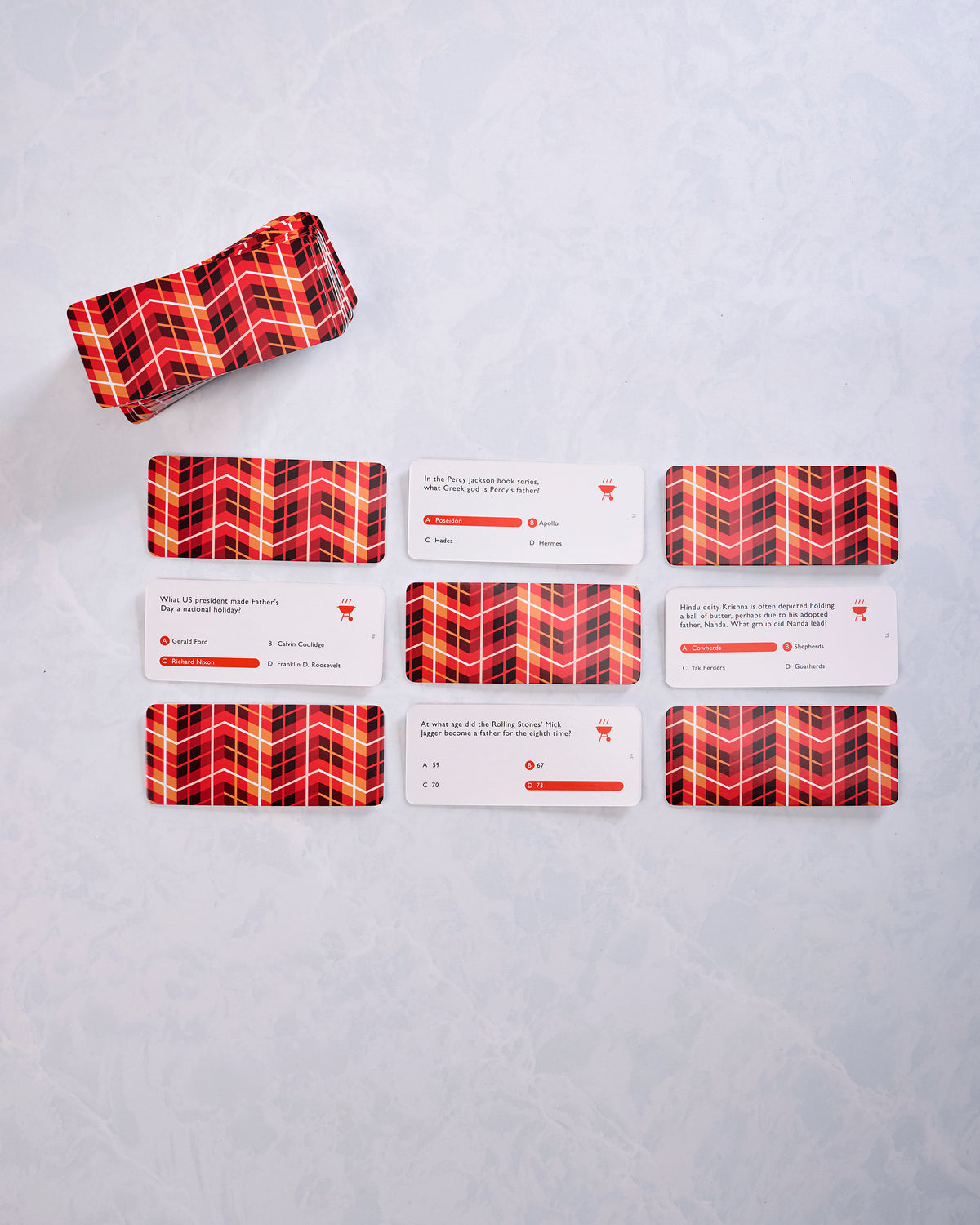 Dad Trivia cards and red patterned card backs arranged in rows beside the matching storage box.