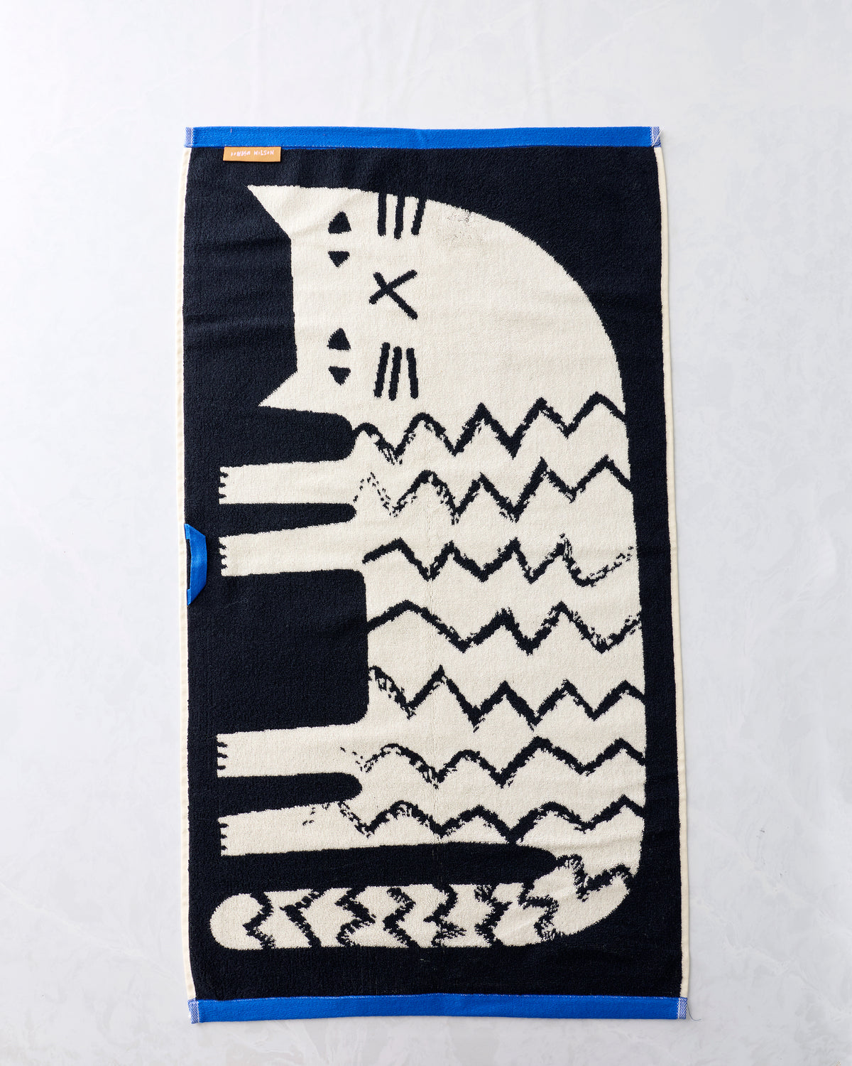 Black and cream Lazy Cat hand towel displayed flat, featuring a cat face and repeated zigzag cat pattern.