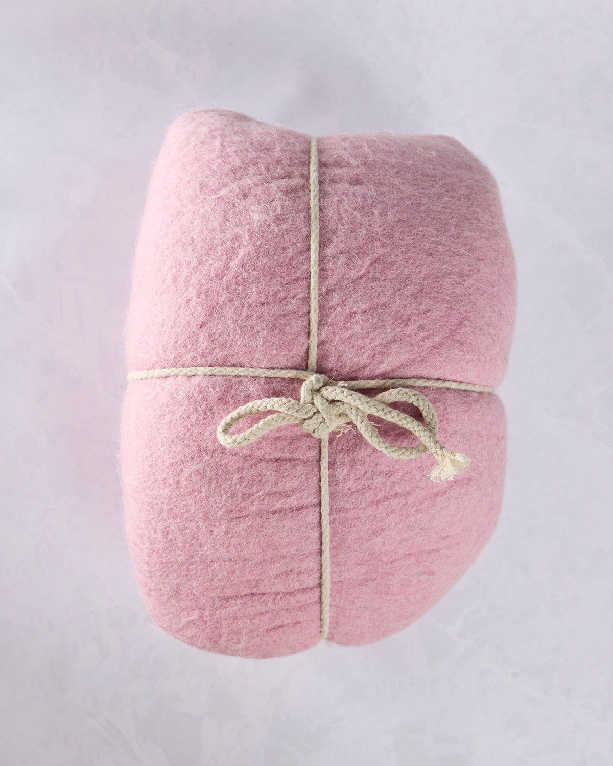Pink felted wool cat cave bed wrapped with a rope for storage or display.