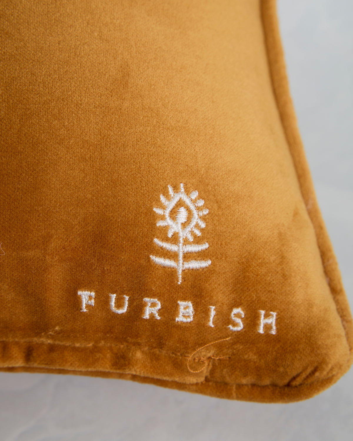 Close-up of the orange pillow backing with an embroidered Furbish logo.