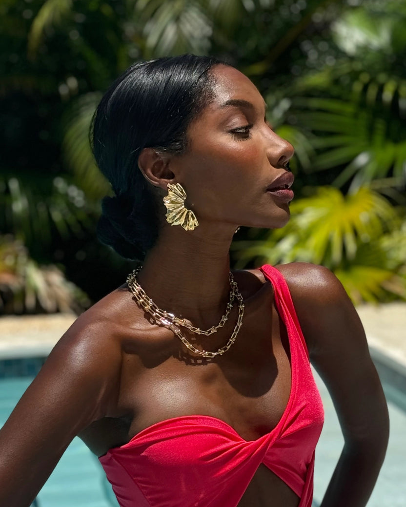 Side view of a person wearing a gold fan-shaped Arabella earring