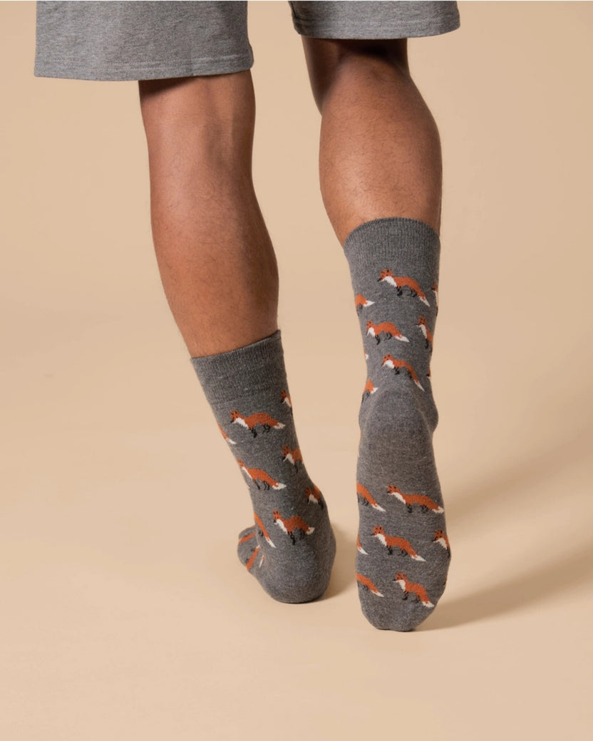 Gray crew socks with repeated fox motifs shown being worn on lower legs and feet.
