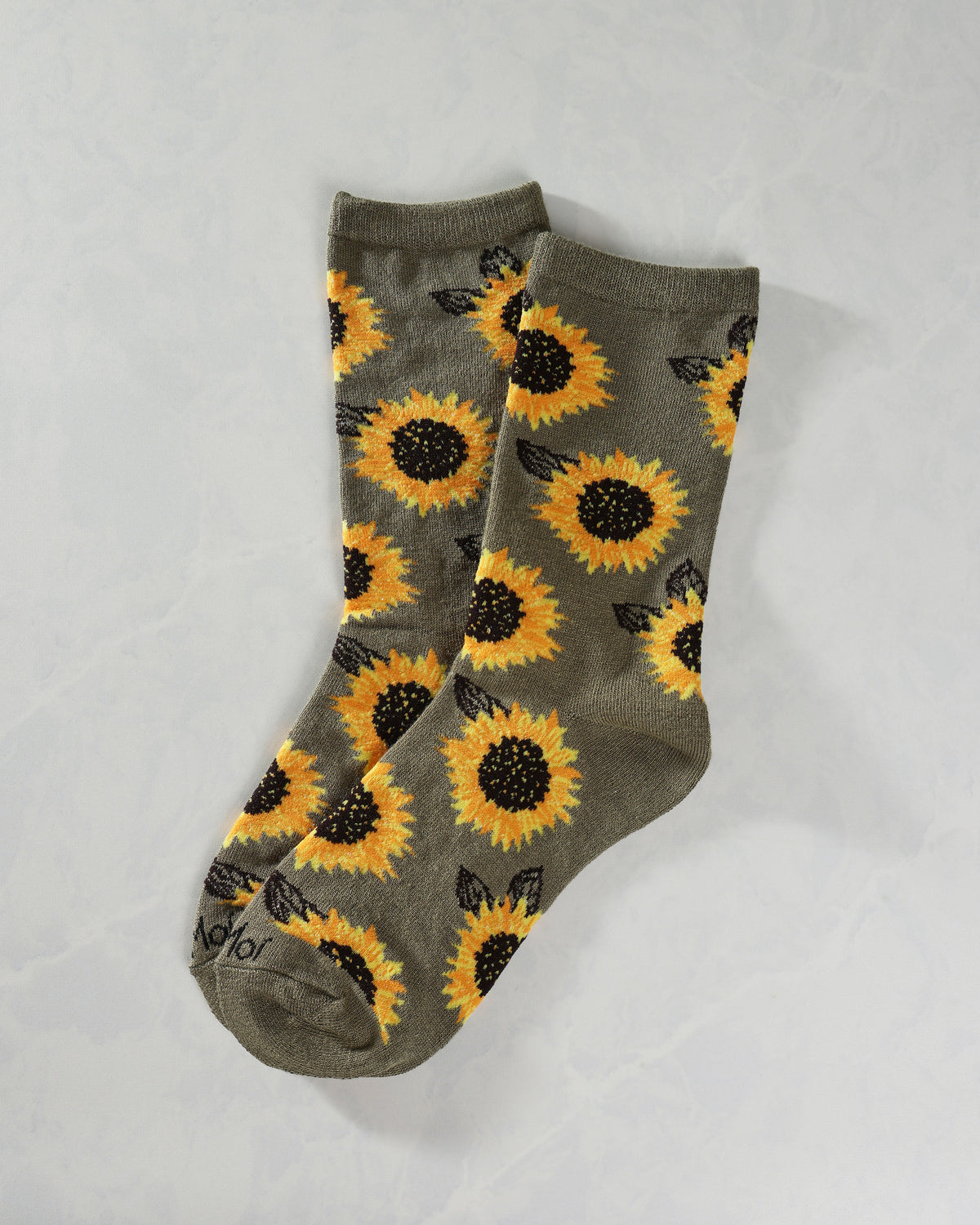 Pair of olive crew socks with an all-over yellow sunflower and black leaf pattern, shown overlapping.
