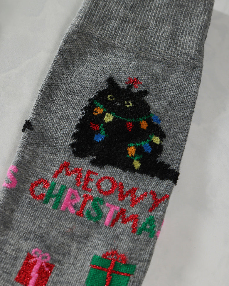 Close-up of a gray sock showing an embroidered black cat with Christmas lights and festive lettering