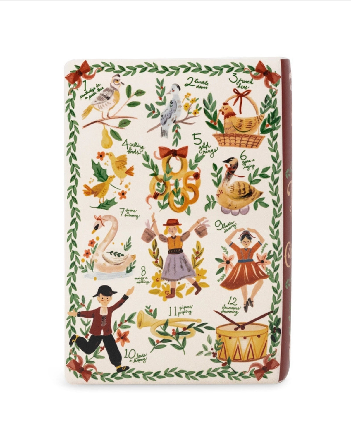 Front view of an ivory ceramic book-shaped vase with a Twelve Days of Christmas illustration, leafy border, and wide top opening.