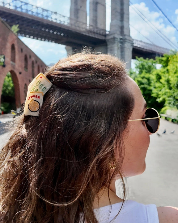 Person wearing a mahjong-tile hair claw clip securing the back of their hair outdoors.