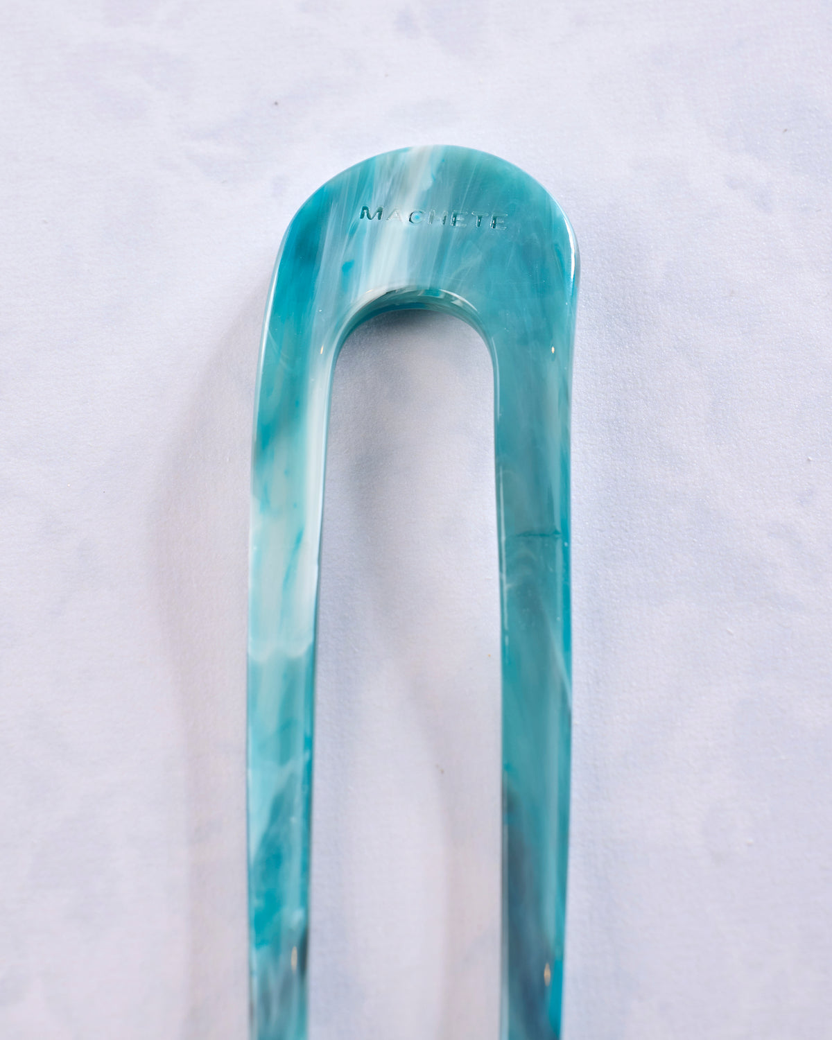 Close-up of the teal marbled end of a Machete French hair pin.