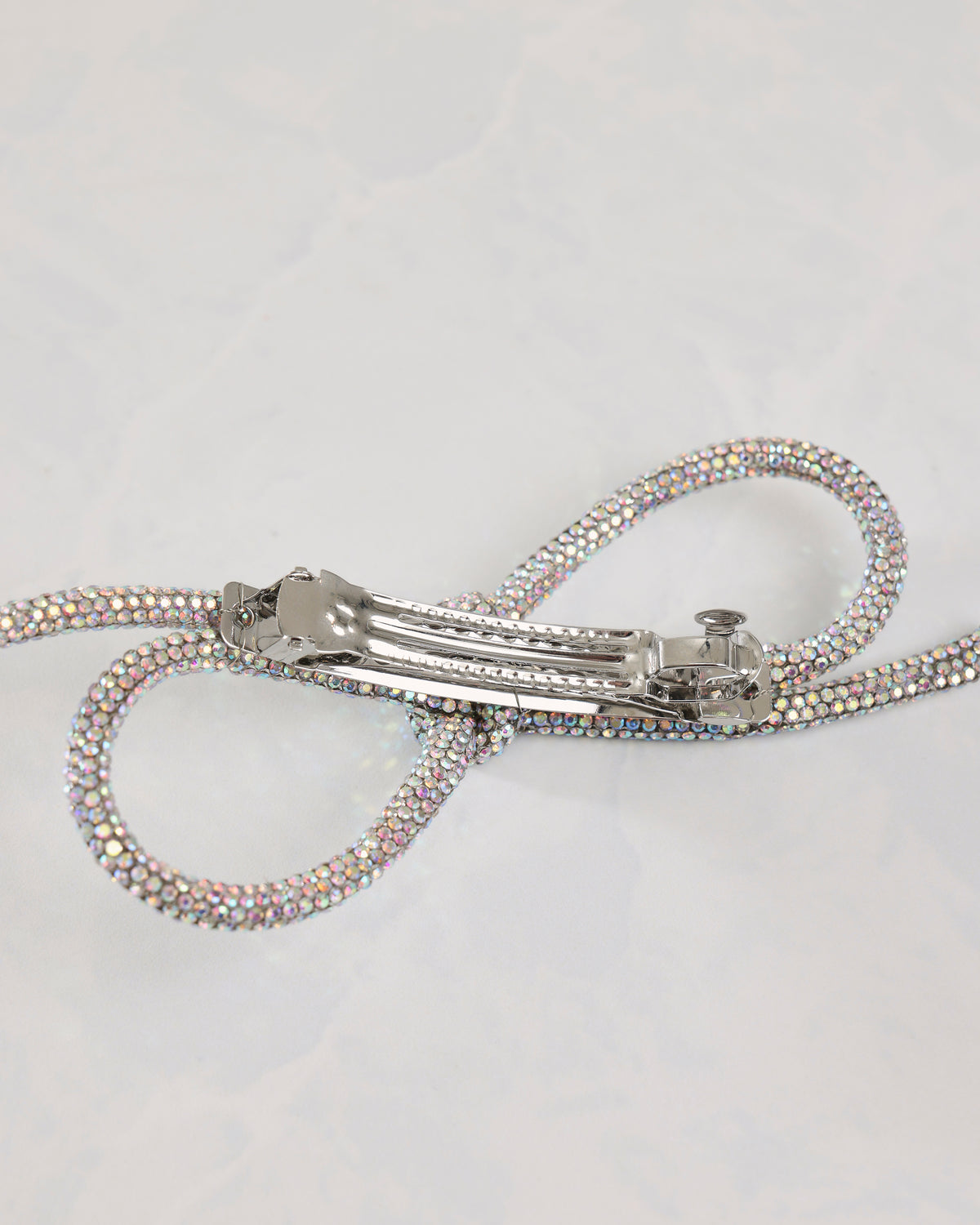 Silver sparkling bow barrette shown from the back with its metal hair clip
