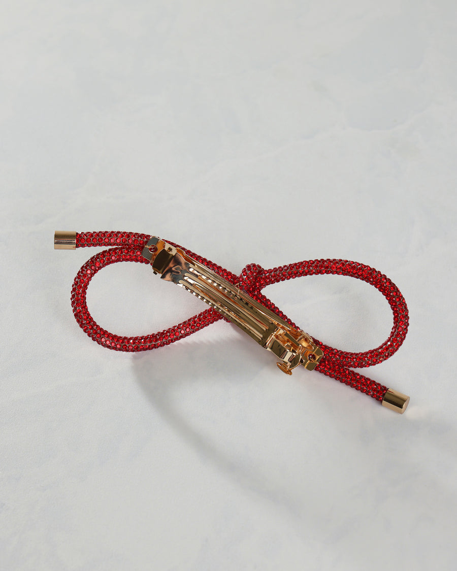 Red sparkling bow barrette shown from the back with its metal hair clip