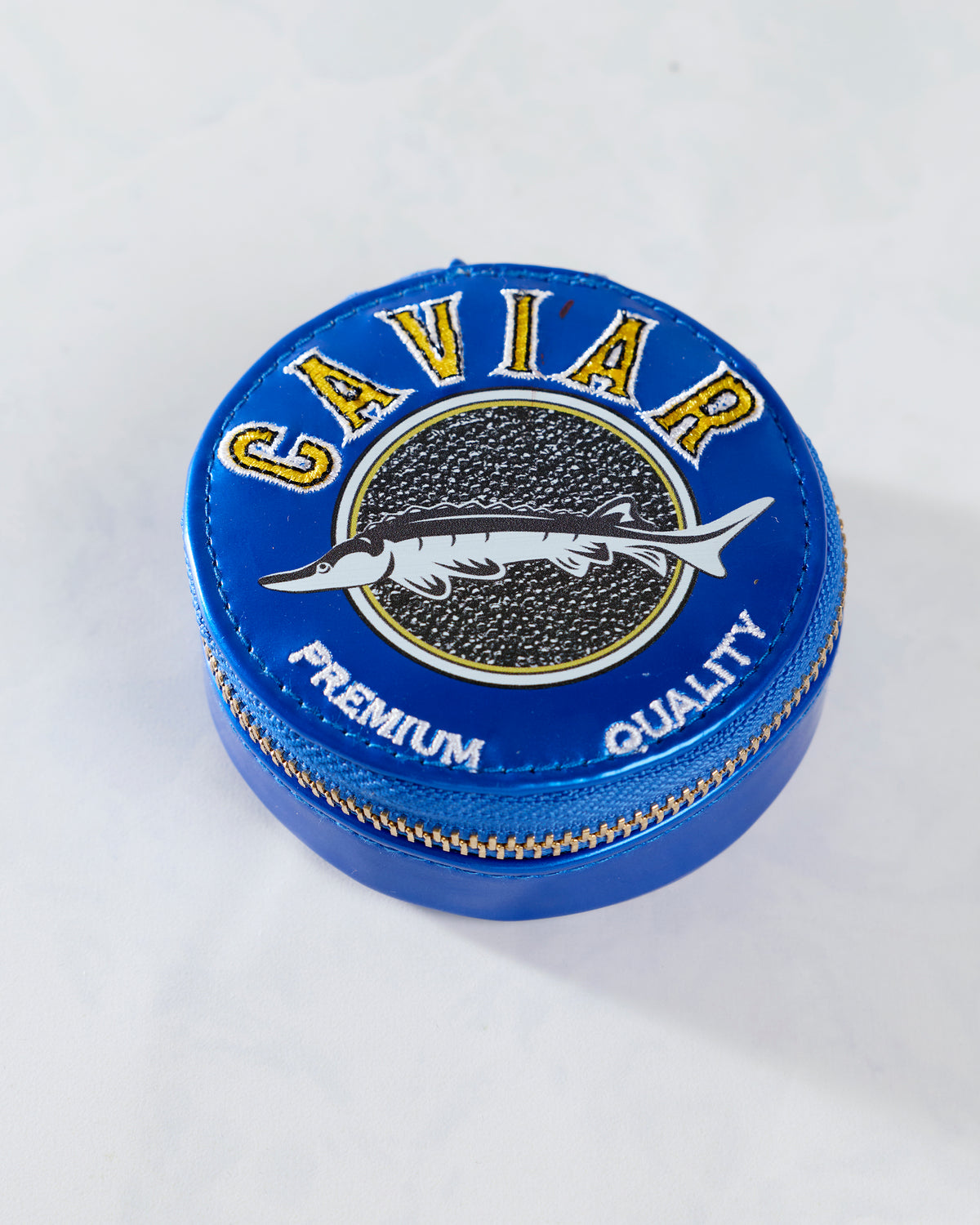 Closed blue round pill case with a fish graphic and the words CAVIAR and PREMIUM QUALITY on the lid.