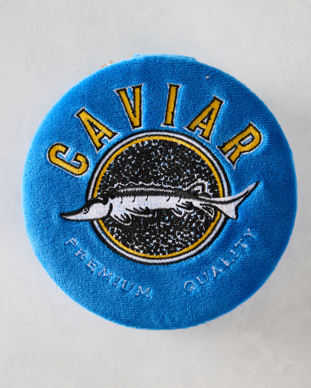 Closed blue velvet jewelry zip case with embroidered yellow, black, and white swordfish emblem and lettering.