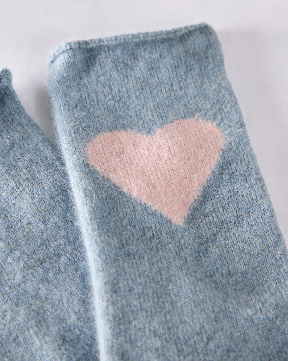Close-up of a blue crew sock with a pink heart motif.