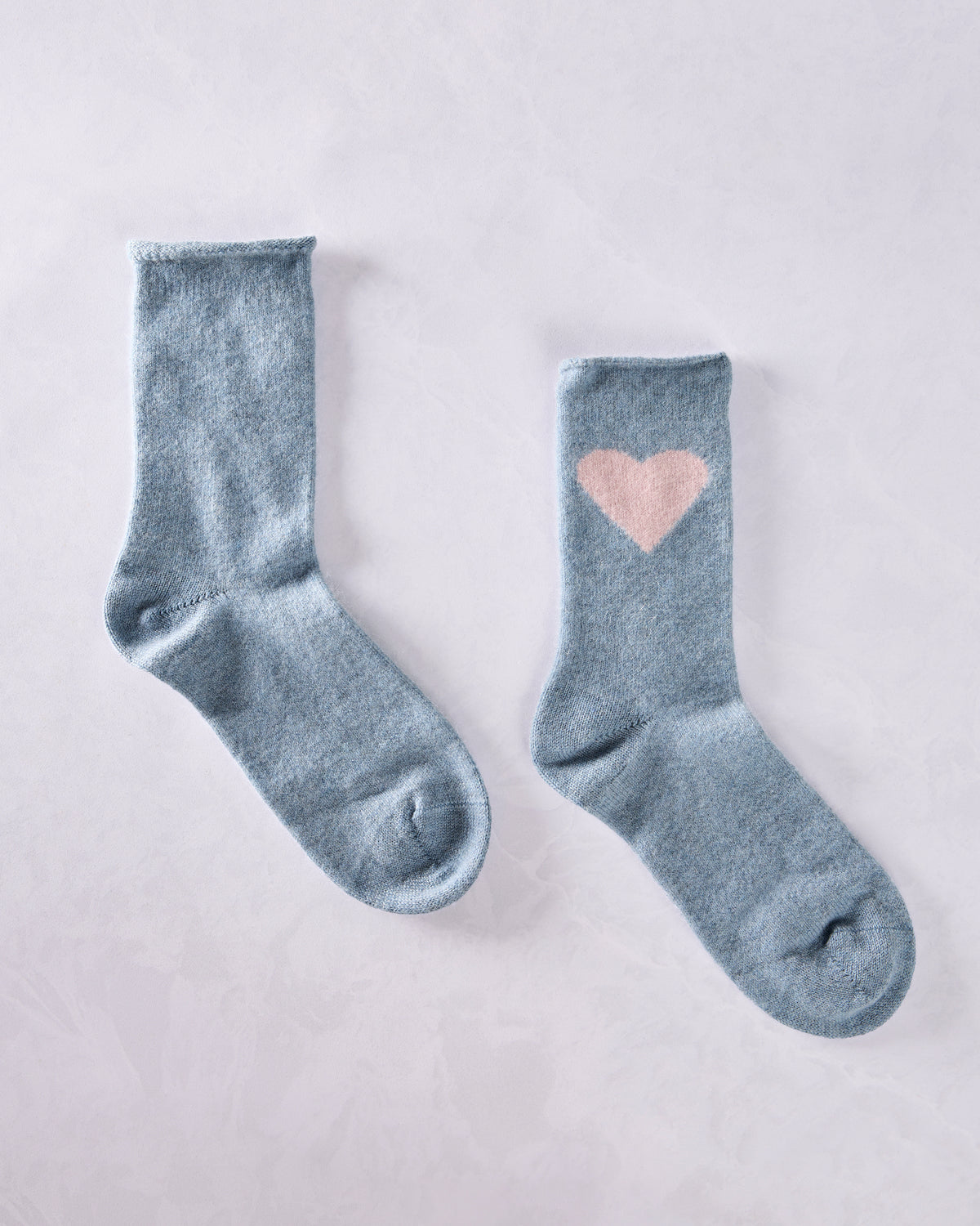 Pair of blue crew socks, with a pink heart motif visible on one sock.