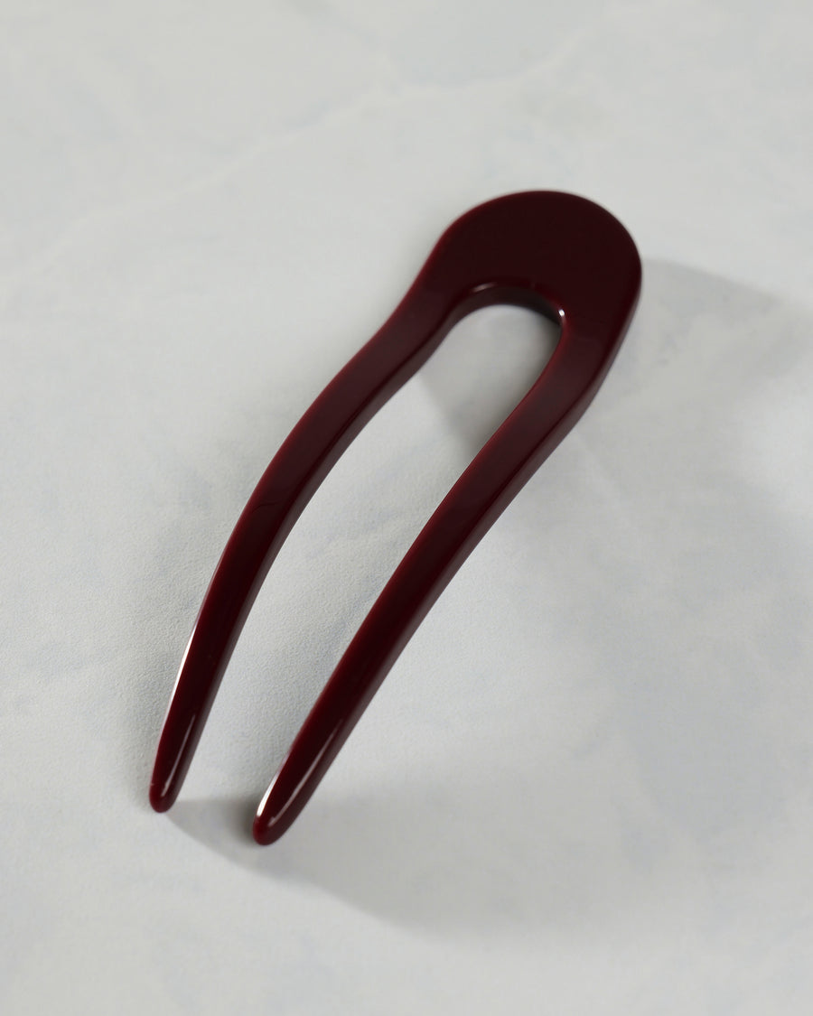 Oxblood French hair pin with a long U-shaped design on a white surface.