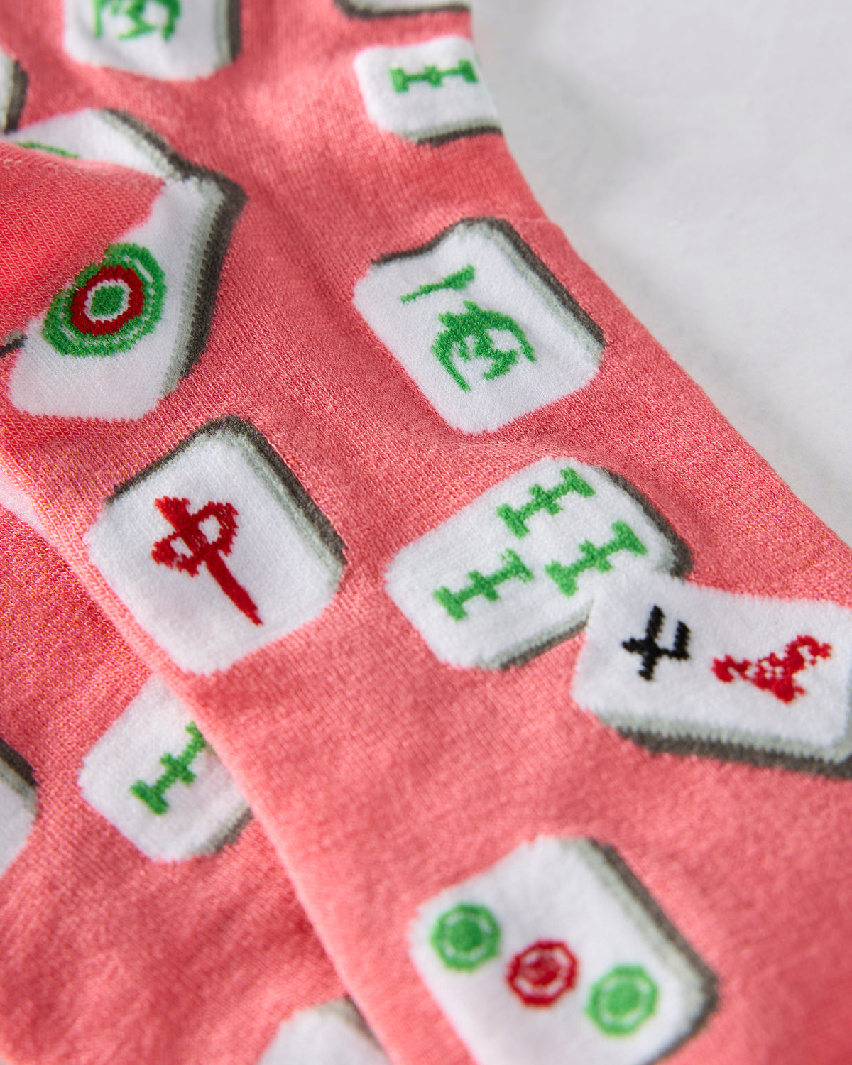 Close-up of the pink sock fabric and repeated mahjong tile pattern in red, green, black, and white.