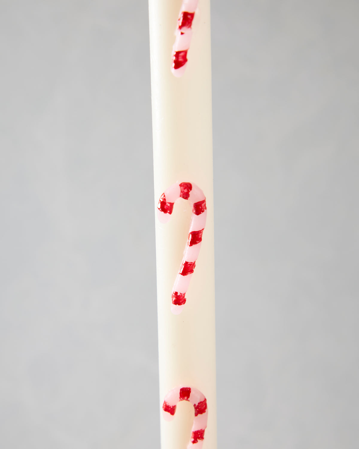 Close-up of a white candle with pink and red candy-cane stripes.