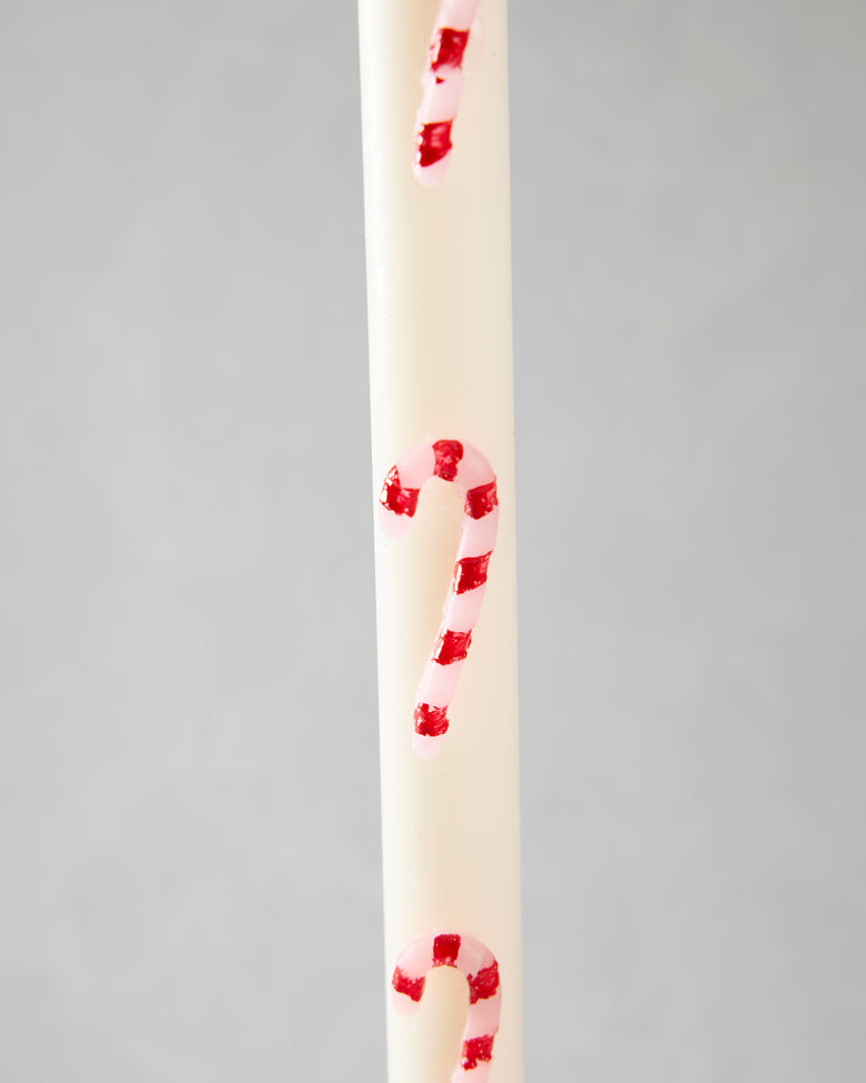 Close-up of a white candle with pink and red candy-cane stripes.