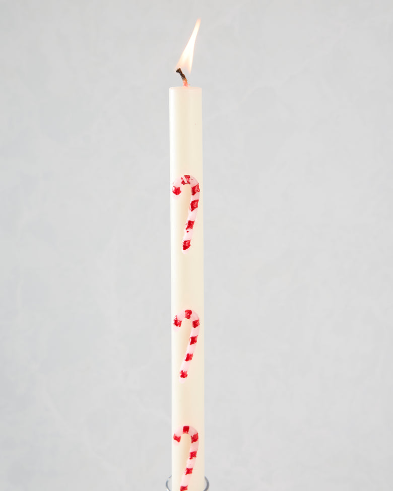 Lit white candle with pink and red candy-cane stripes.