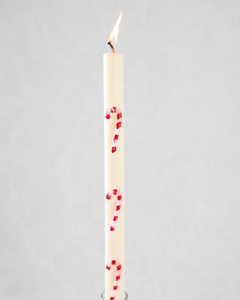Lit white candle with pink and red candy-cane stripes.
