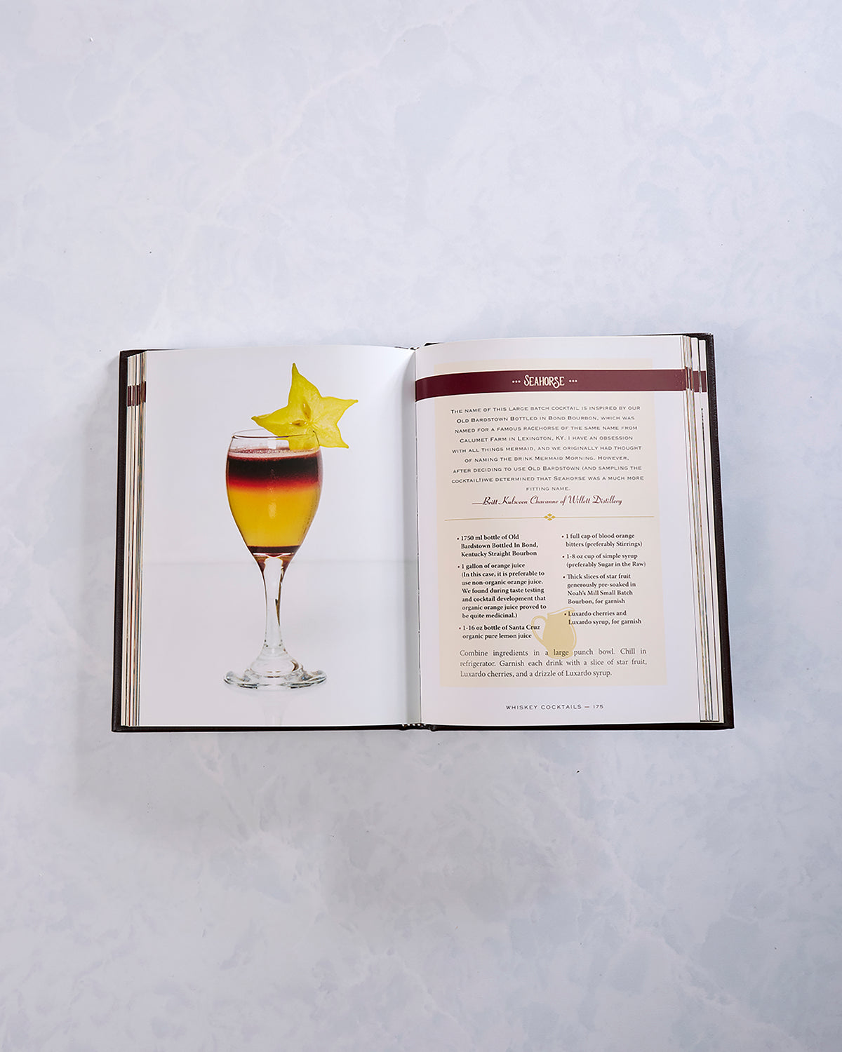 Open spread from “Whiskey Cocktails” showing a layered cocktail garnished with a star fruit beside a cocktail recipe page.