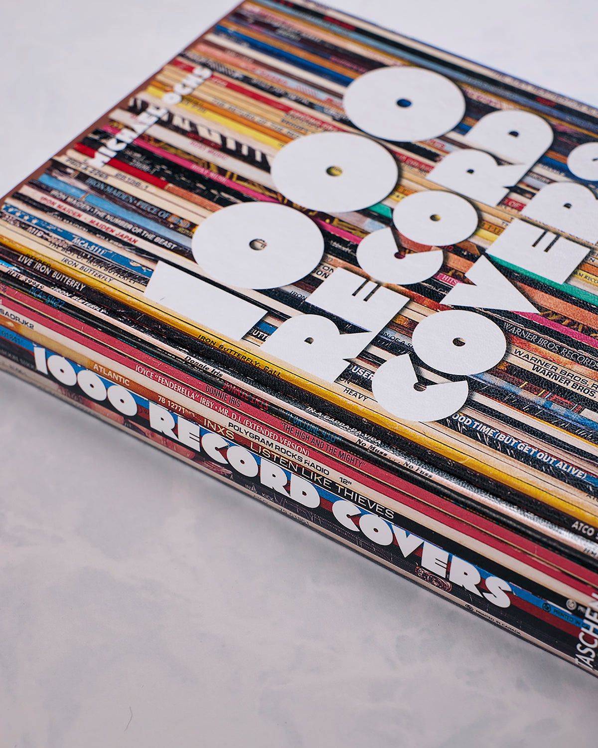 Close-up of a large book featuring a collage of record sleeves, with white cutout shapes arranged on top.