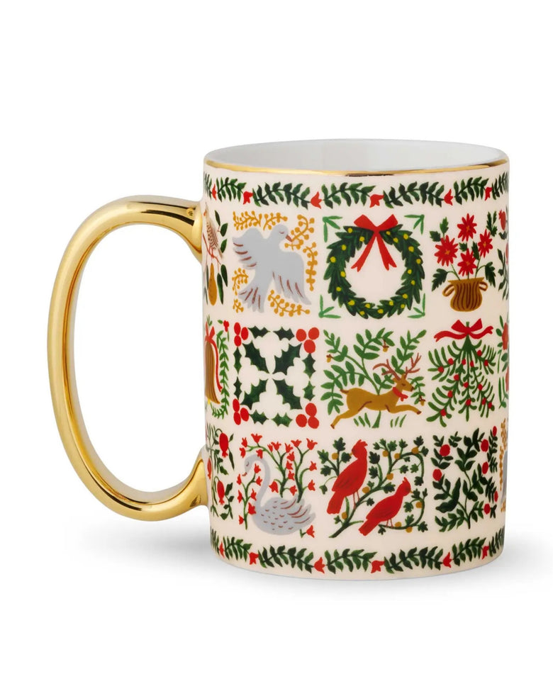 White Christmastide mug with a gold handle and colorful holiday illustrations around the exterior.