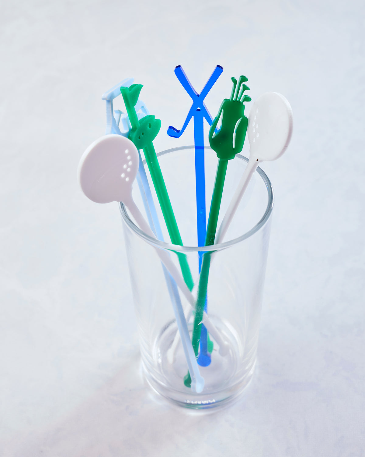 Five colorful golf-themed stir sticks displayed upright in a clear glass.