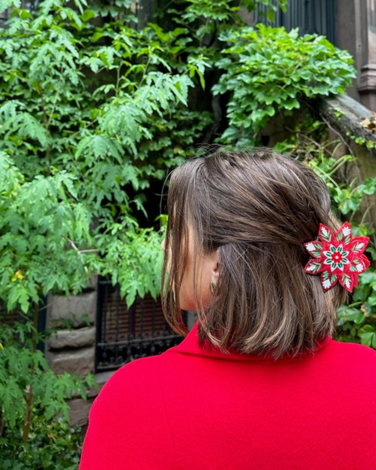 Christmas flower claw clip securing hair, shown from the rear outdoors.