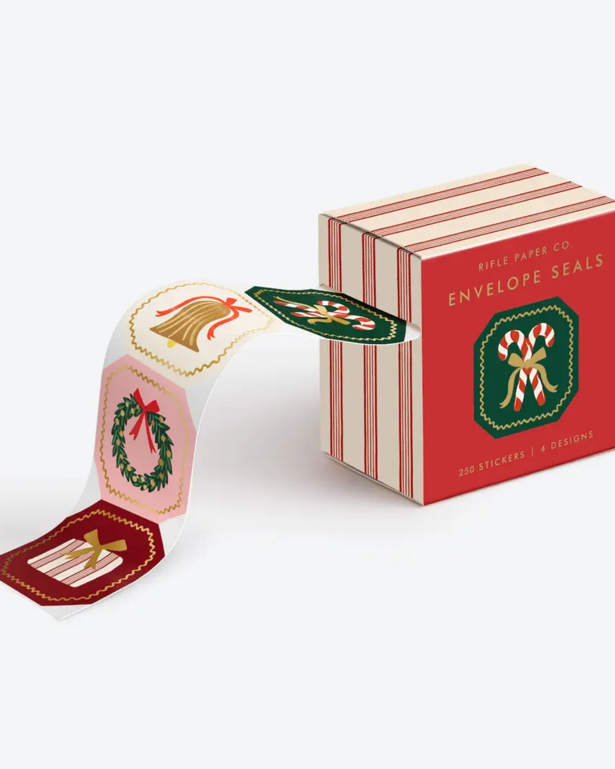 Roll of holiday envelope seals unwinding from a red-and-cream box, showing wreath, bell, and candy-cane designs.
