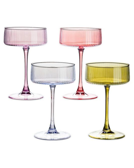 Four ribbed cocktail coupe glasses with long stems in pink, red, clear blue, and yellow.