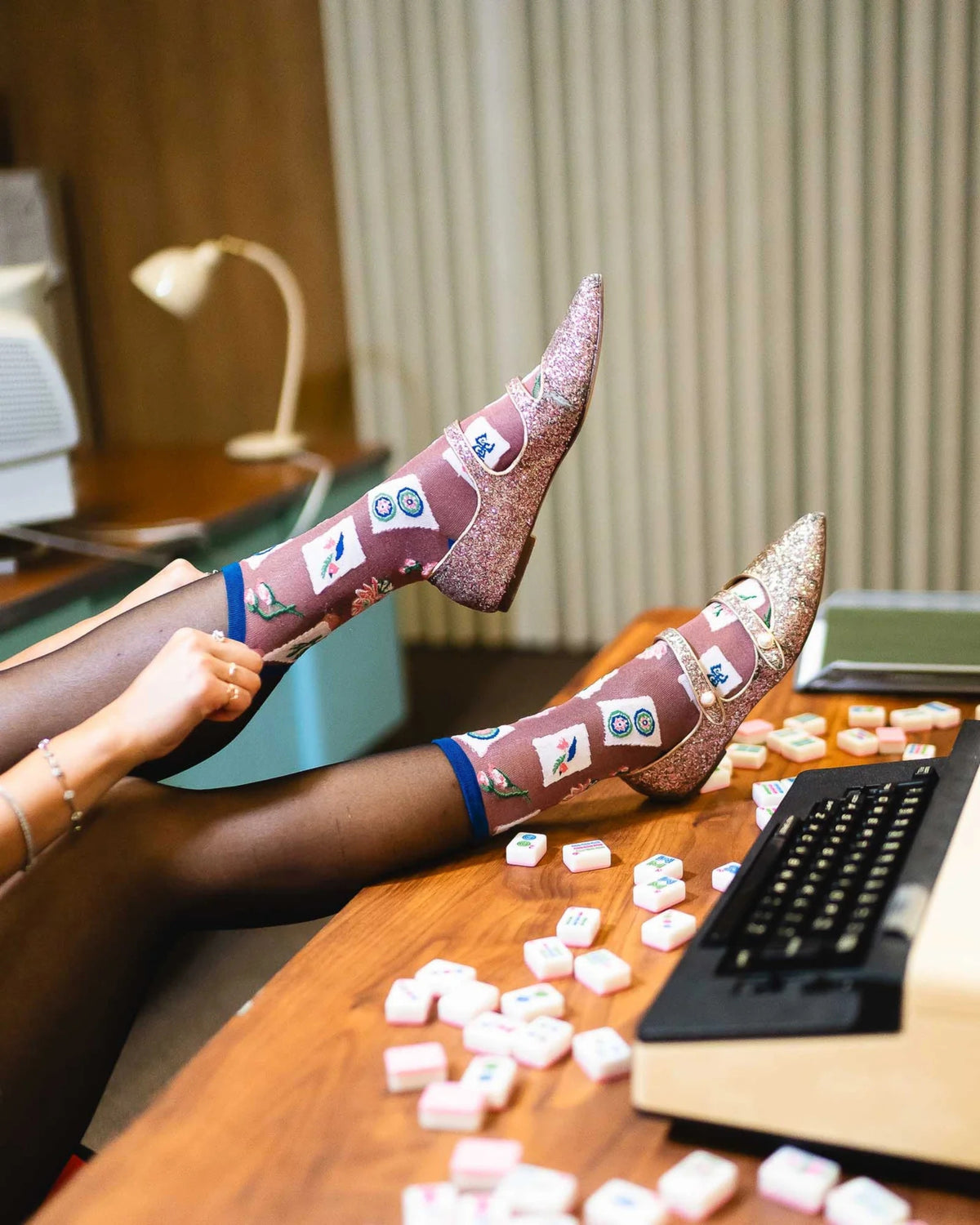 Sheer mahjong tile socks with blue trim shown with glitter pointed heels while worn.