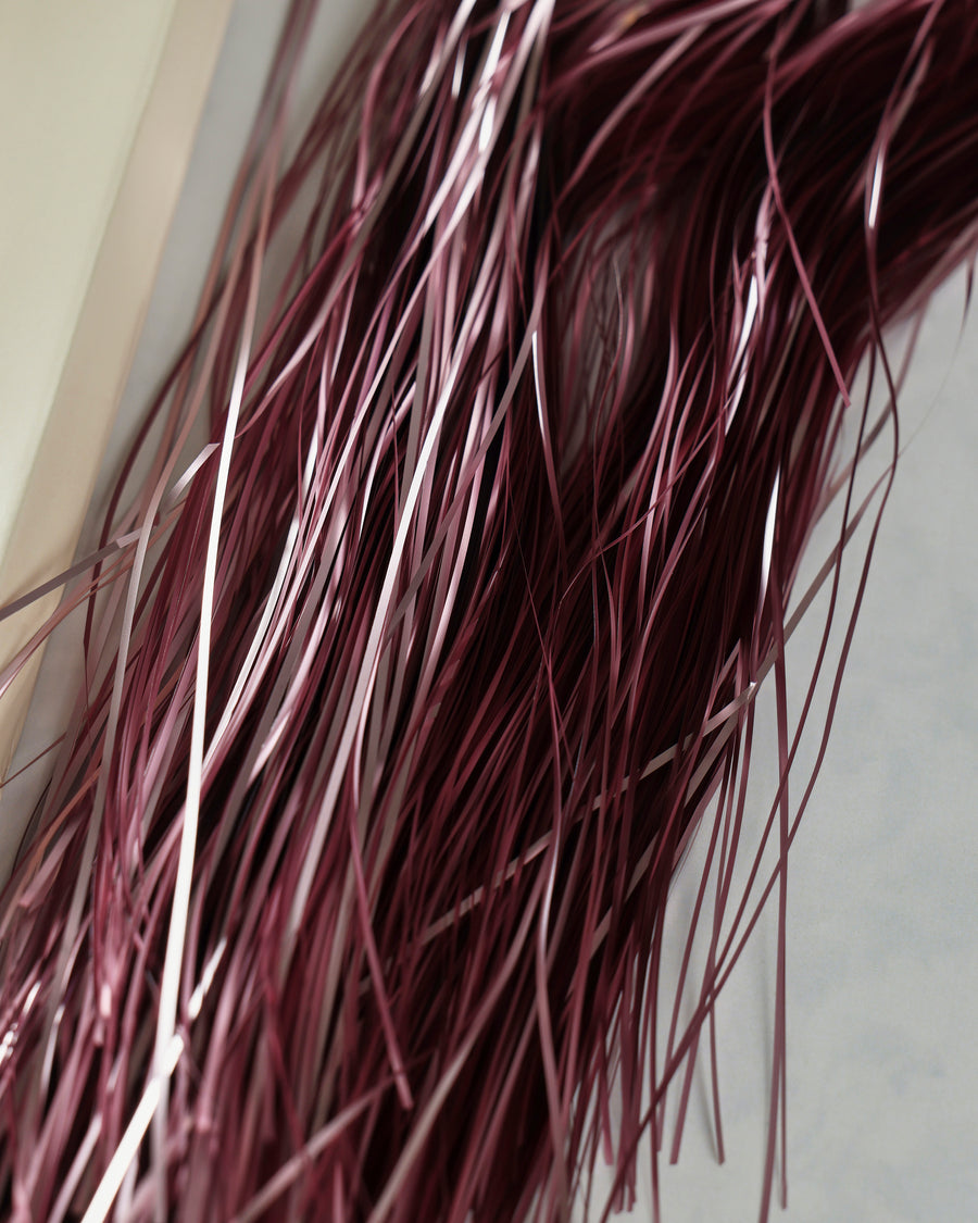 Close-up of thin pink metallic tinsel strands showing varied reflective highlights.