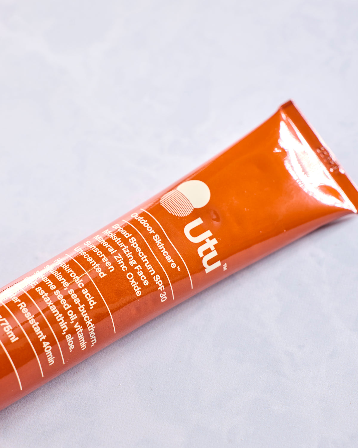 Close-up of the orange Utu sunscreen tube showing its SPF 30 and skincare labeling.