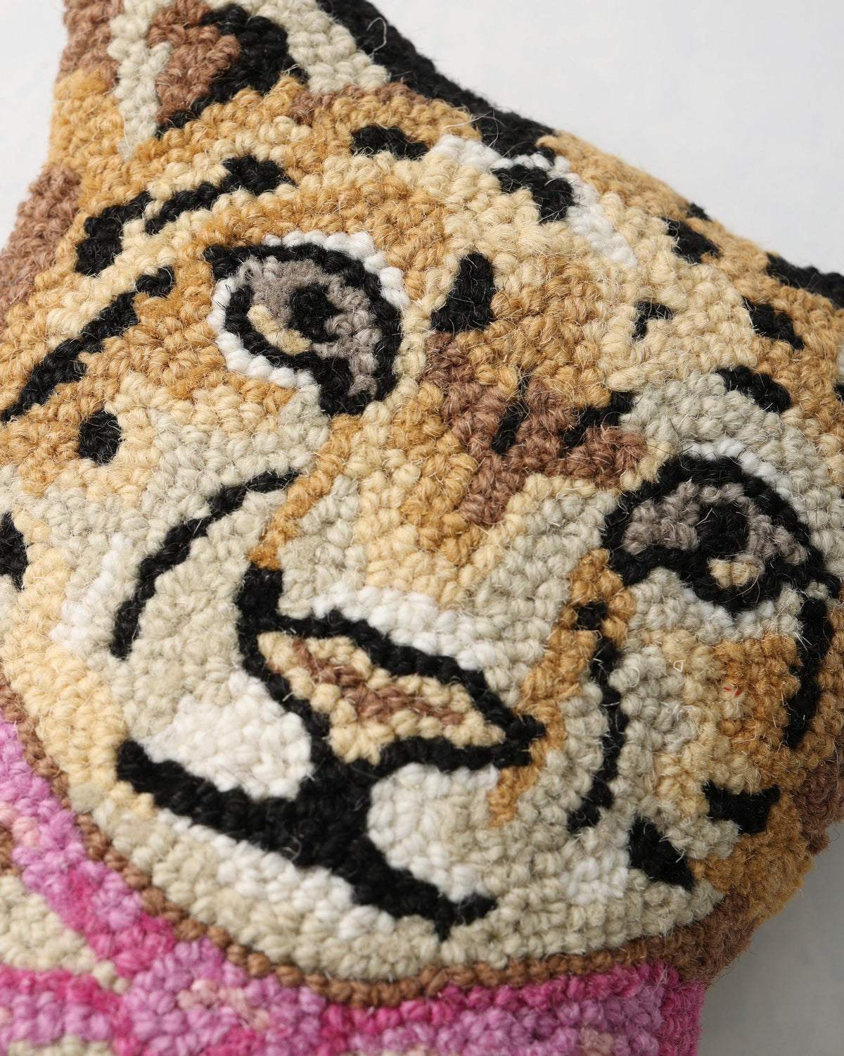 Close-up of the hooked leopard pillow’s face and pink bow detail.