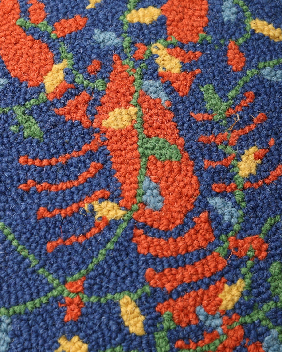 Close-up of the colorful hooked lobster design and botanical accents on the navy pillow.