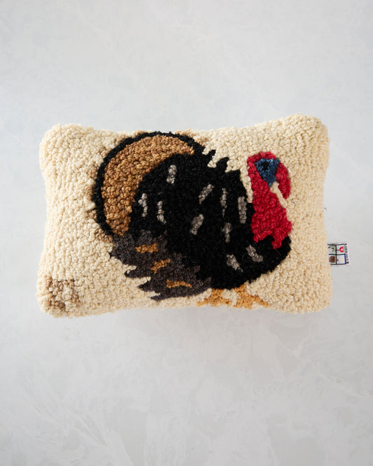 Front view of an ivory Perky Turkey pillow with a large black turkey illustration, brown hat, and red accent.