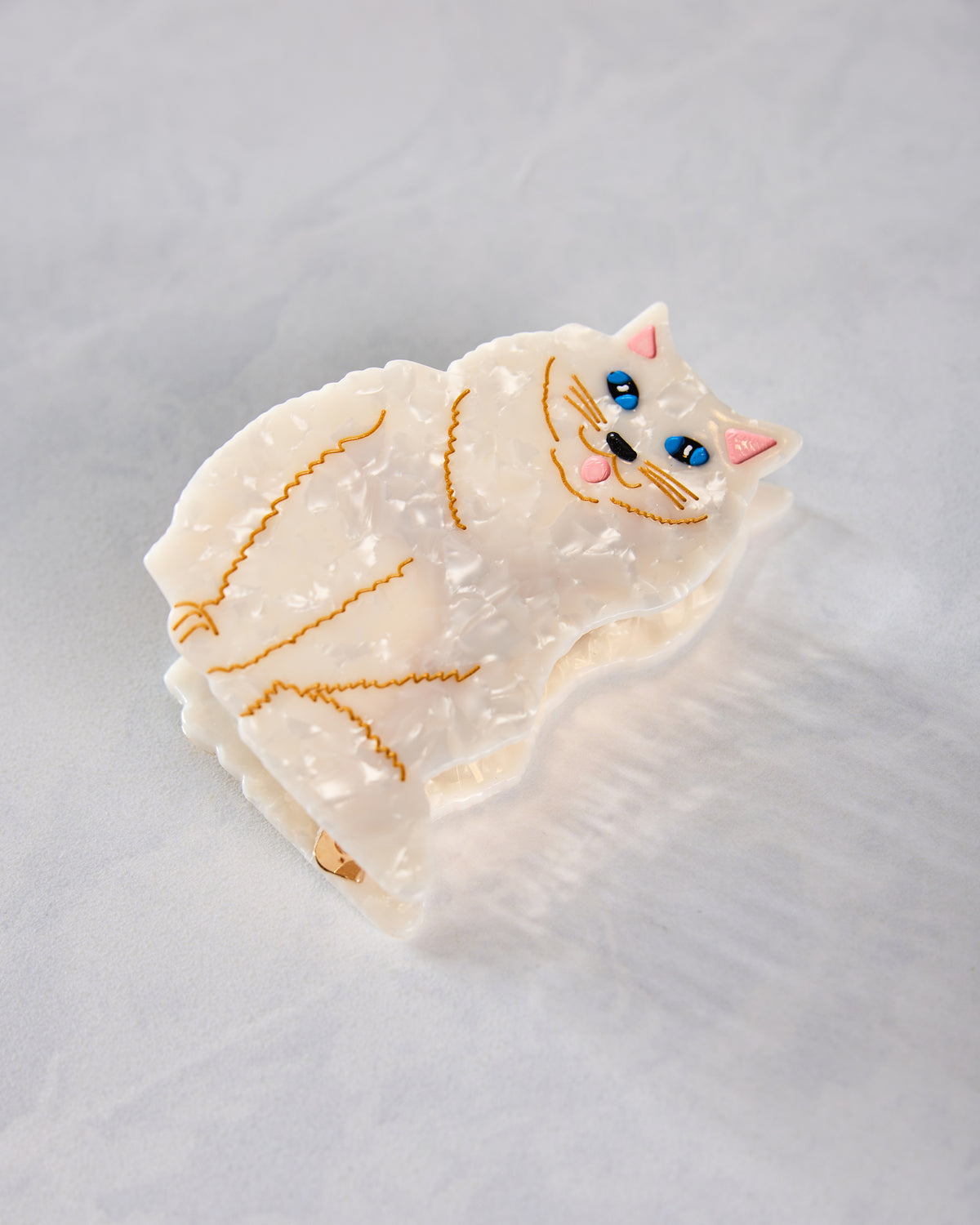 White hand-painted Persian cat claw hair clip lying flat, showing the full cat design and clip edge.