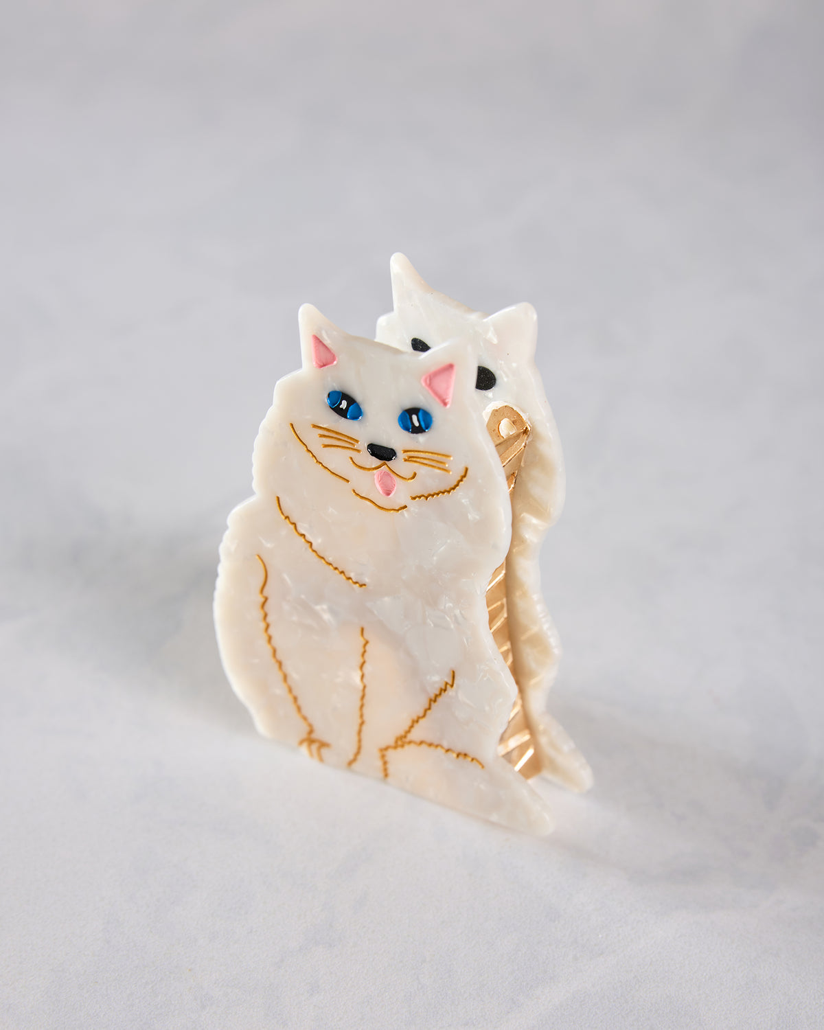 Angled front view of a white hand-painted Persian cat claw hair clip, with the cat face and clip teeth visible.
