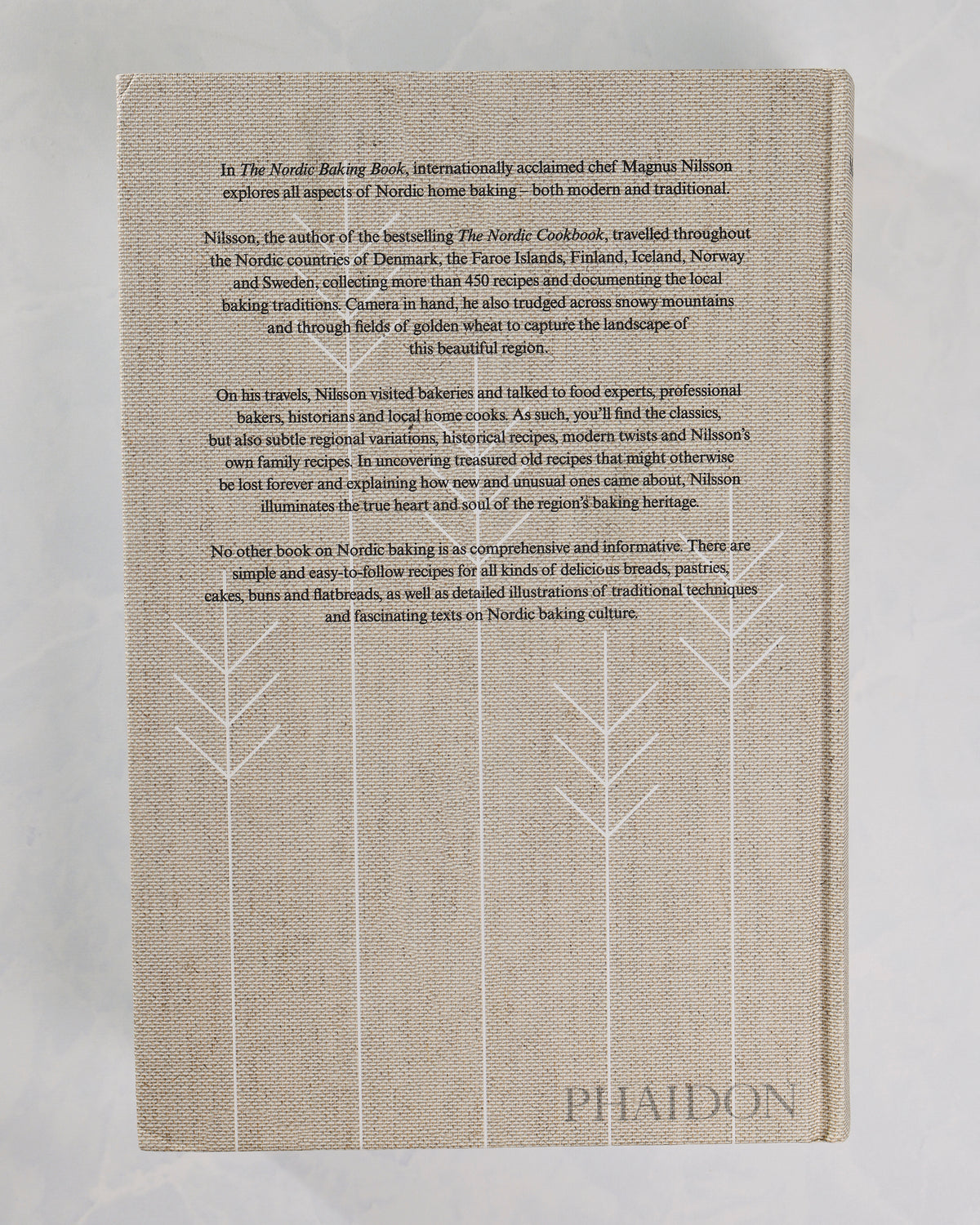 Back cover of The Nordic Baking Book with a centered description of the book and white stylized tree outlines.