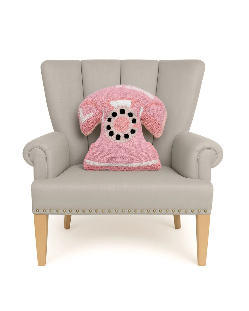 Pink telephone-shaped hook pillow displayed on a light upholstered armchair