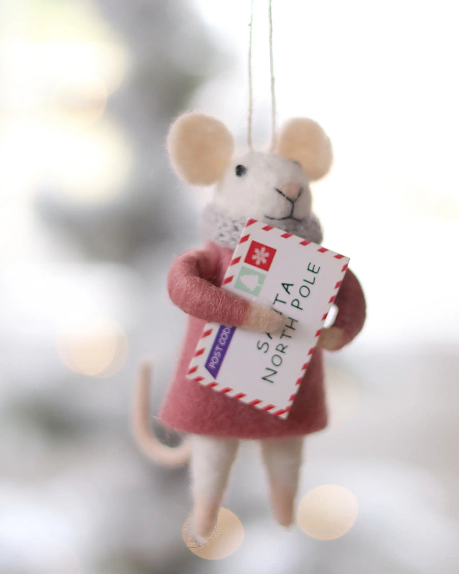 Felt mouse ornament holding a Santa North Pole envelope, shown hanging against a softly blurred background.