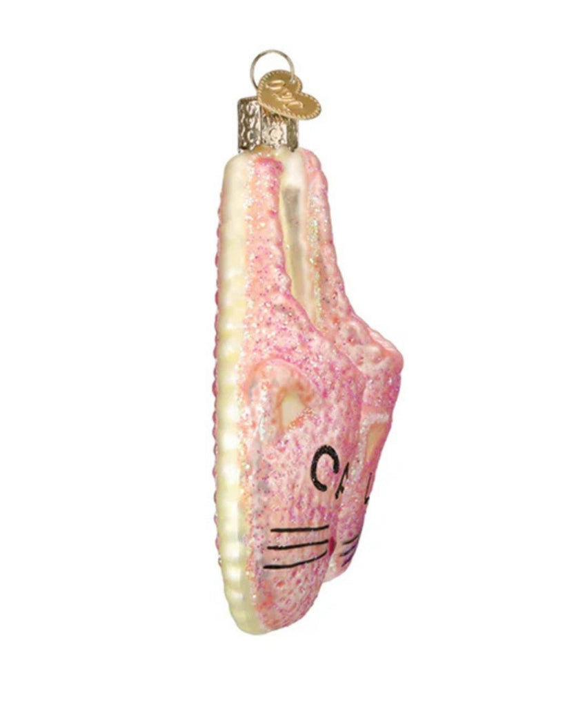 Side view of a pink glitter cat slipper ornament showing its raised slipper shape, cream-colored sole edge, and hanging loop.