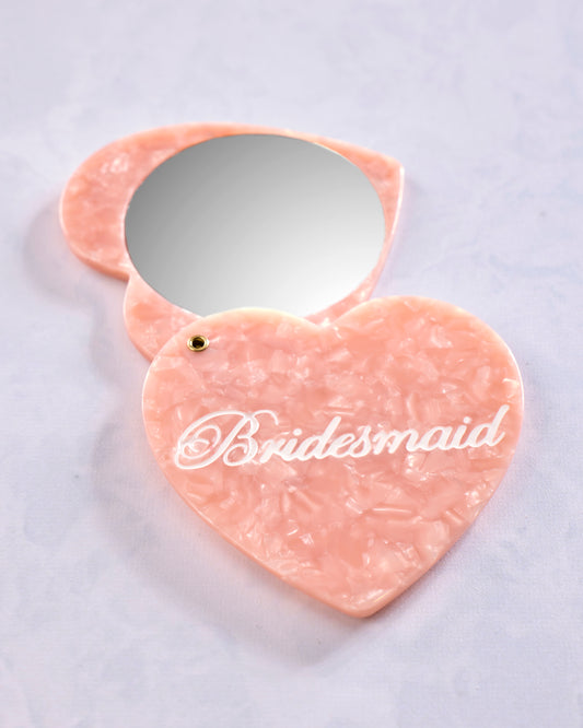 Open heart-shaped compact mirror with a pink marbled exterior and “Bridesmaid” printed on the front.