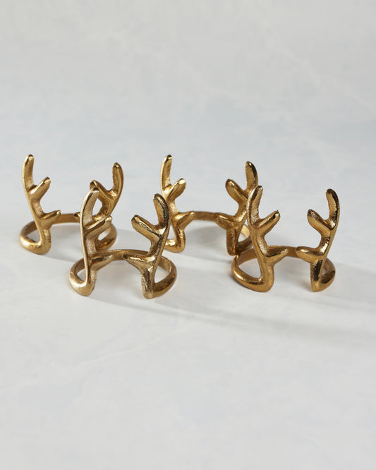 Several gold antlers napkin rings arranged in two rows on a white surface.