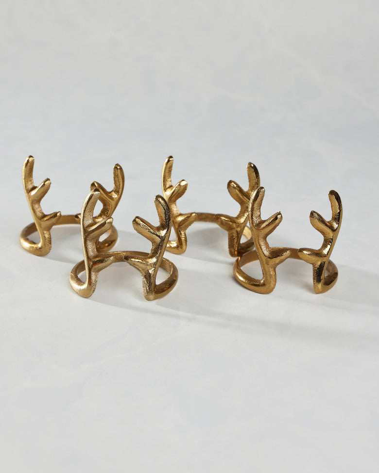 Several gold antlers napkin rings arranged in two rows on a white surface.