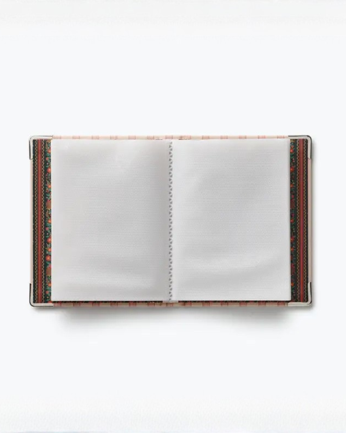 Open small photo album showing blank pages, patterned inner covers, and metal corner protectors.