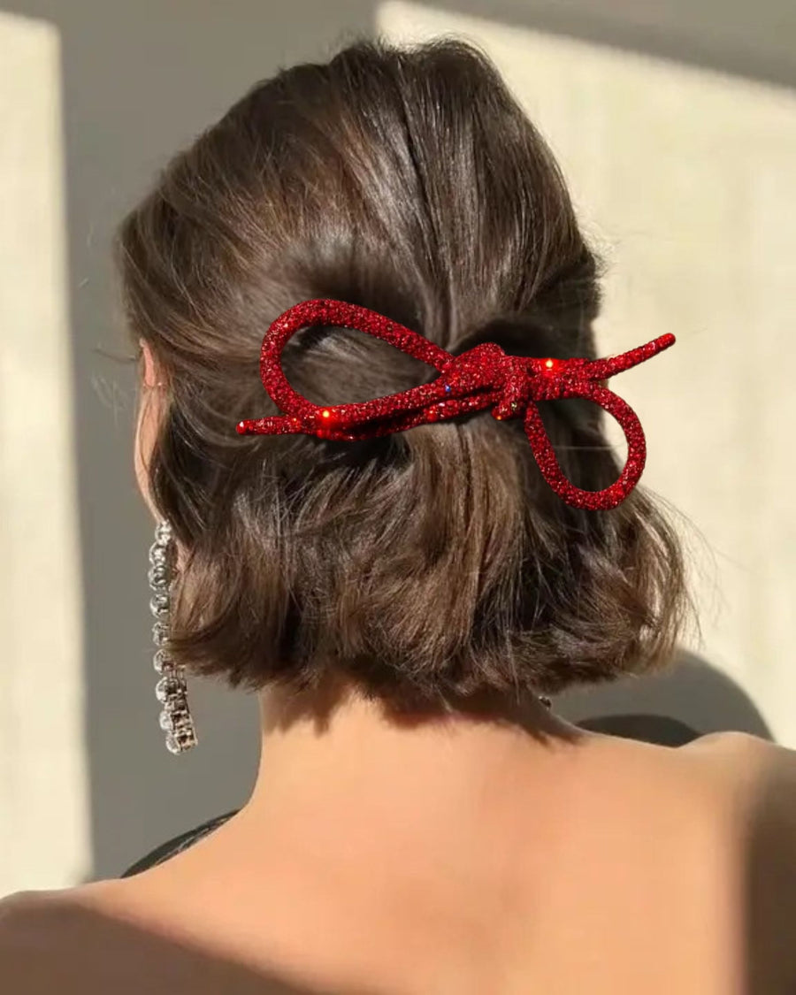 Red glitter bow barrette clipped into the back of short hair