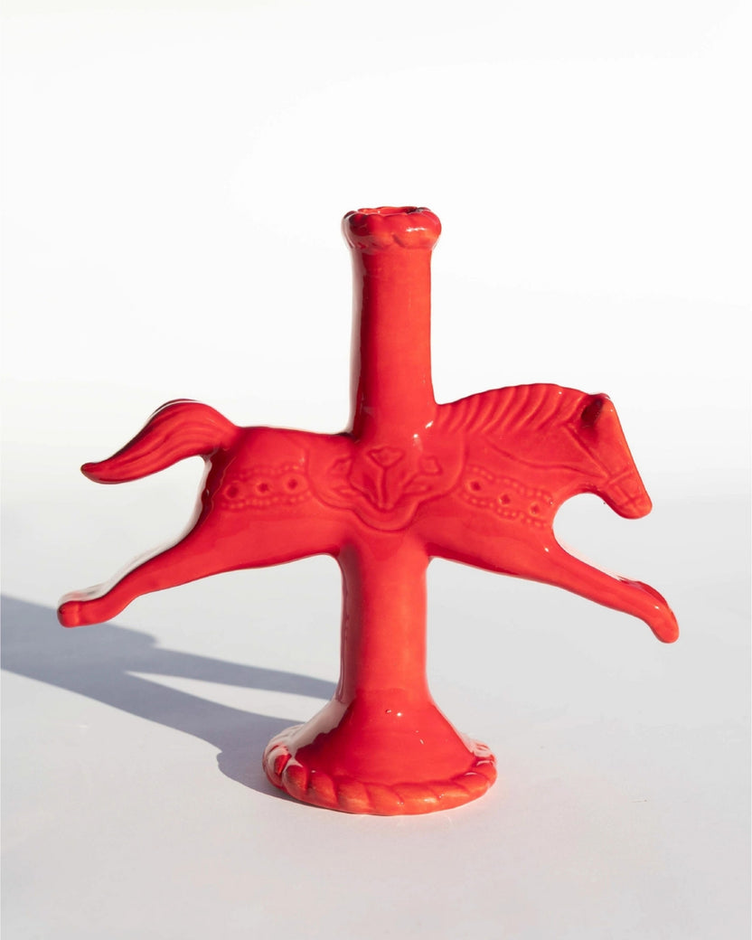 Red sculptural horse-shaped candlestick holder with a central candle opening, shown on a white background.