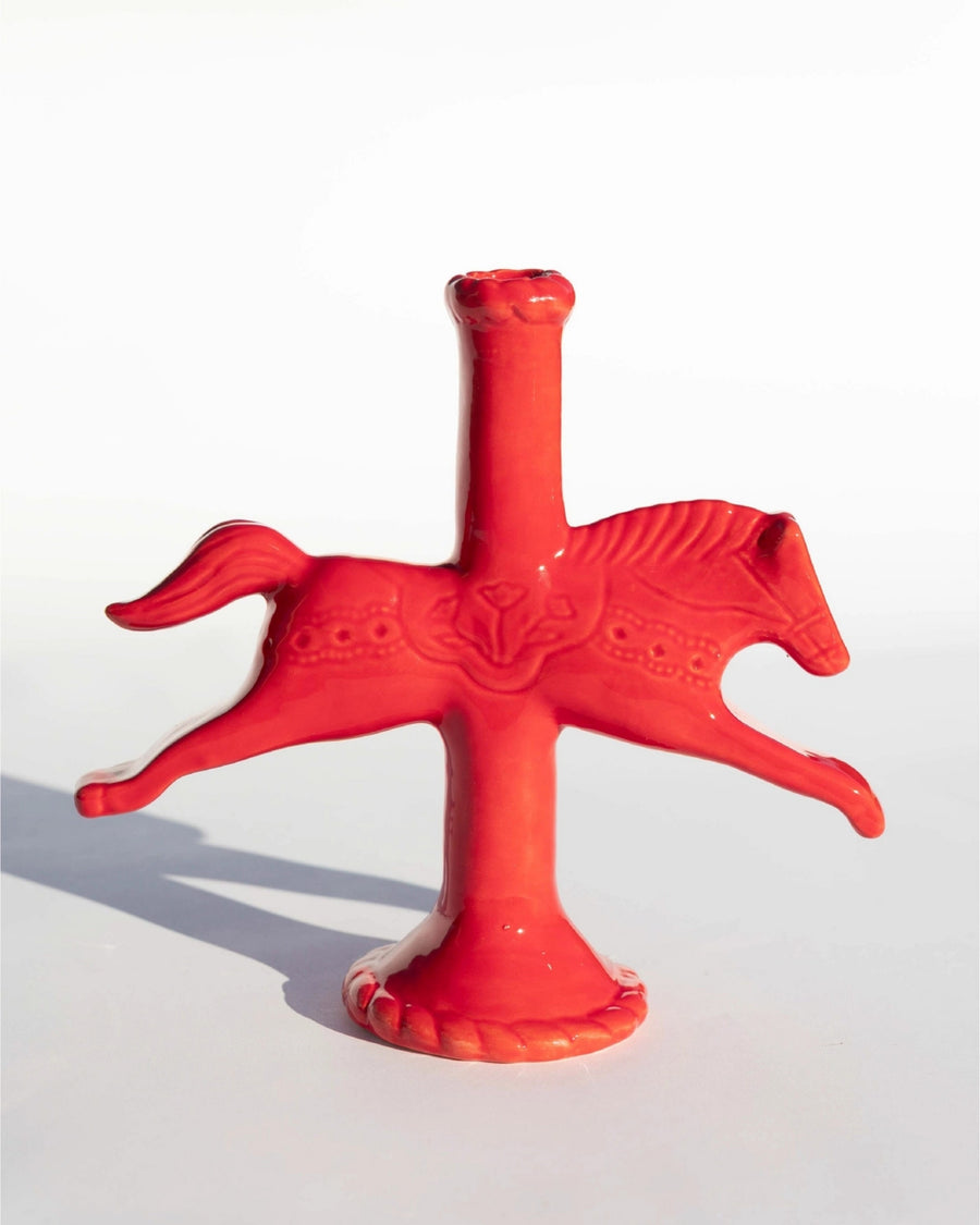 Red sculptural horse-shaped candlestick holder with a central candle opening, shown on a white background.